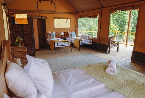 Interior photograph of luxury safari lodge Maasai Mara. With handmade solid oak super-king bed. This tent has views across the natural swimming pool.